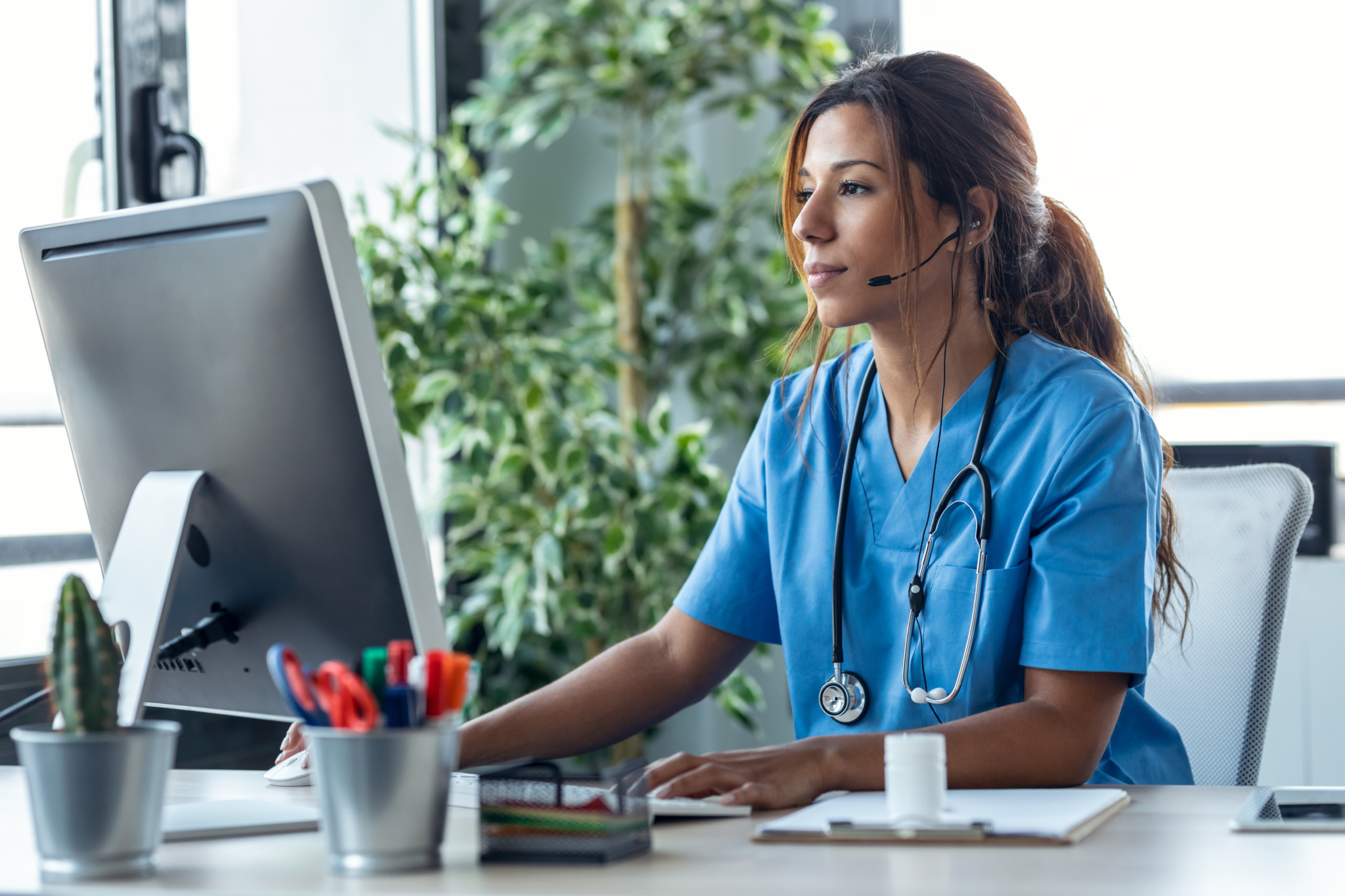 Female doctor talking with earphone while explaining medical treatment to patient through a video call with computer in the consultation.-351