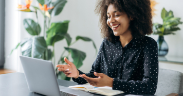 Successful positive young adult woman african woman freelancer, manager, CEO, sitting in office at laptop, talking on video call with client or employees, discussing business strategy, gesturing,smile-821