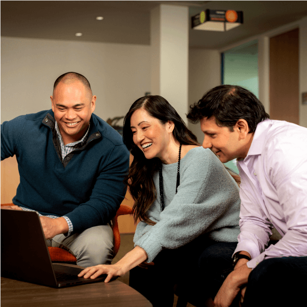 Colleagues collaborate in front of a laptop